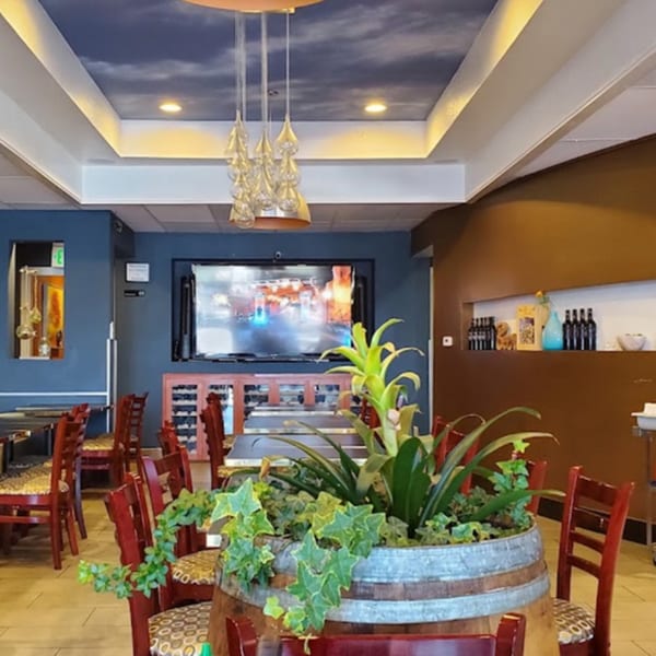 Interior of Pho Tick Tock, with red chairs, a plant in a barrel, and a large TV.