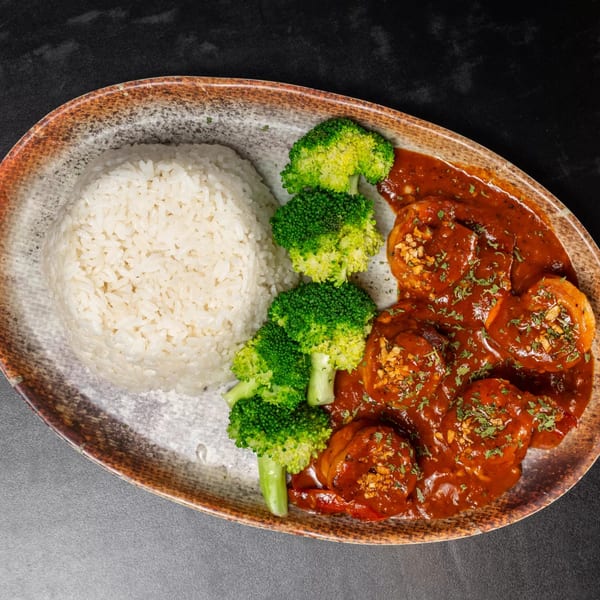 Vietnamese dish with white rice, steamed broccoli, and shrimp in a rich red sauce.