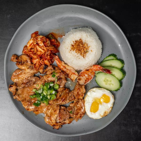 Vietnamese grilled chicken and shrimp with rice, kimchi, cucumbers, and a fried egg.