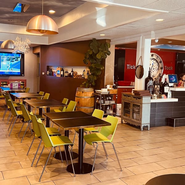 Interior of Pho Tick Tock, showing dining tables with bright green chairs and a bar area.