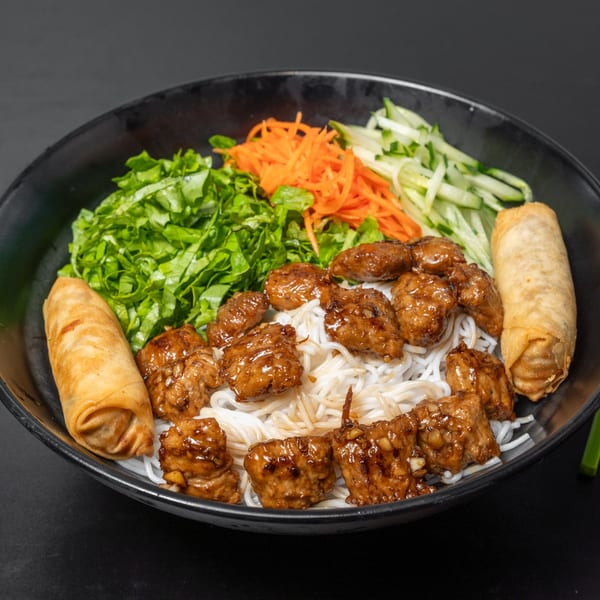 Pho Tick Tock's vermicelli bowl with grilled pork, fresh vegetables, and two crispy spring rolls.