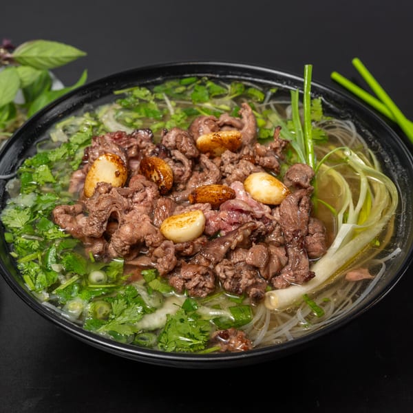Pho Tick Tock's Vietnamese pho with beef, garlic, cilantro, and green onions in a black bowl.